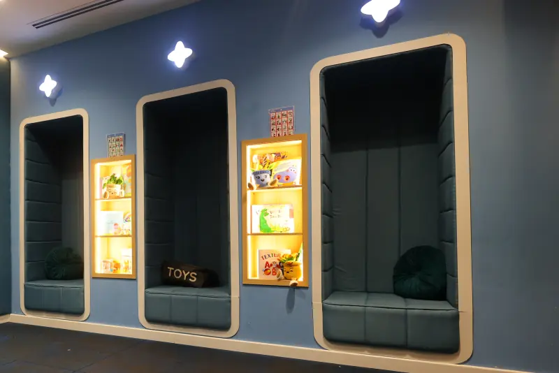 Quiet Room con nichos acolchados para sentarse, repisas iluminadas con libros y tableros de pictogramas